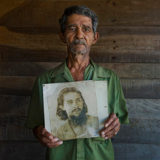 Santiago de Cuba - January 2009.  A veteran of the Cuban revolution holds a portrait of himself taken in 1958 during the revolutionary period.